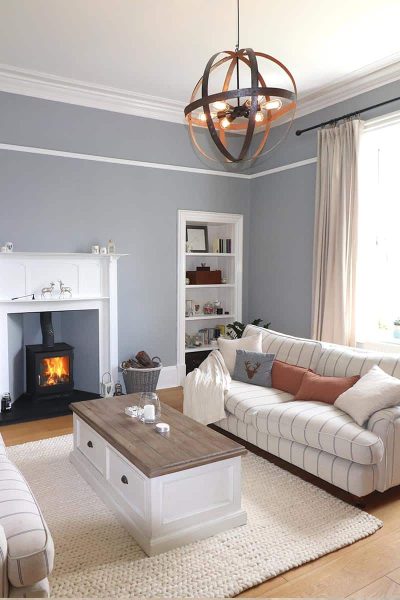 Modern Living Room with a roaring log burner creating a cosy family home. The new wood-burning stove is the Ivar model which is modern looking, and sits well in a traditional fire surround.